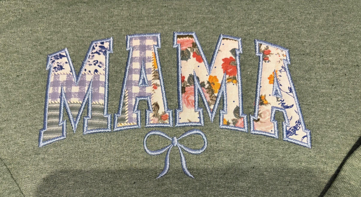 Embroidered appliqued MAMA lettering with floral patches and bow on green fabric
